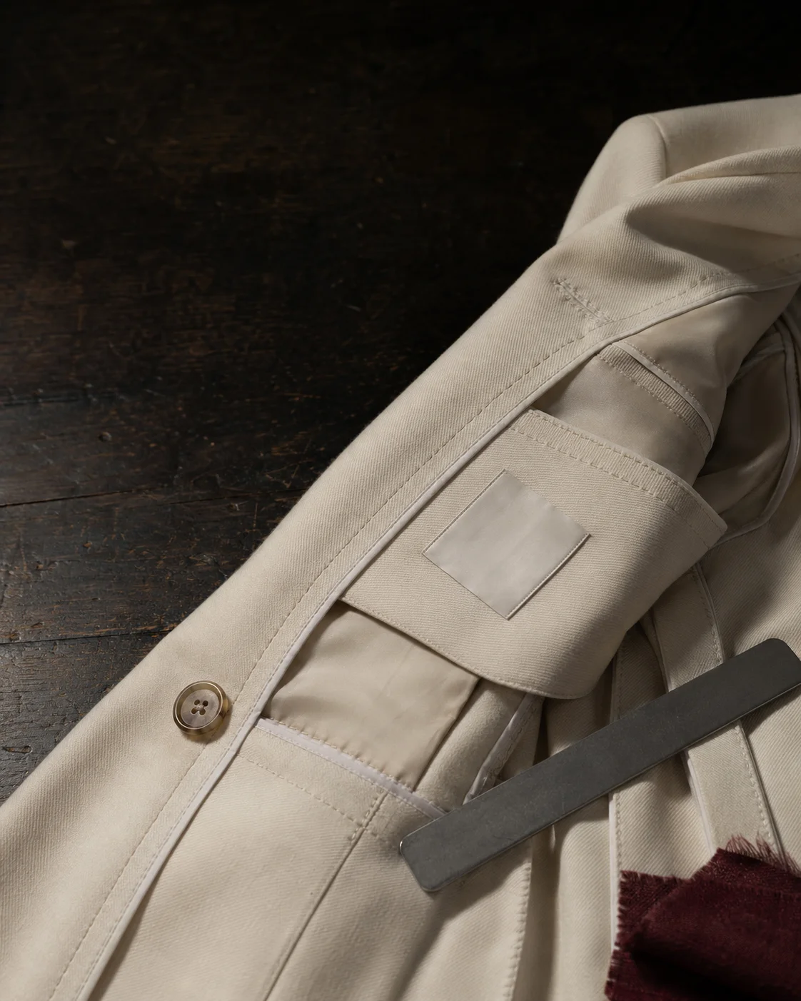 Geöffneter cremefarbener Blazer mit Innenetikett und Schneiderlineal auf einem Arbeitstisch.